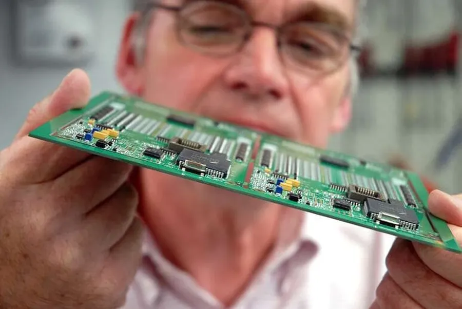 A technician inspecting a PCB using quality control equipment.