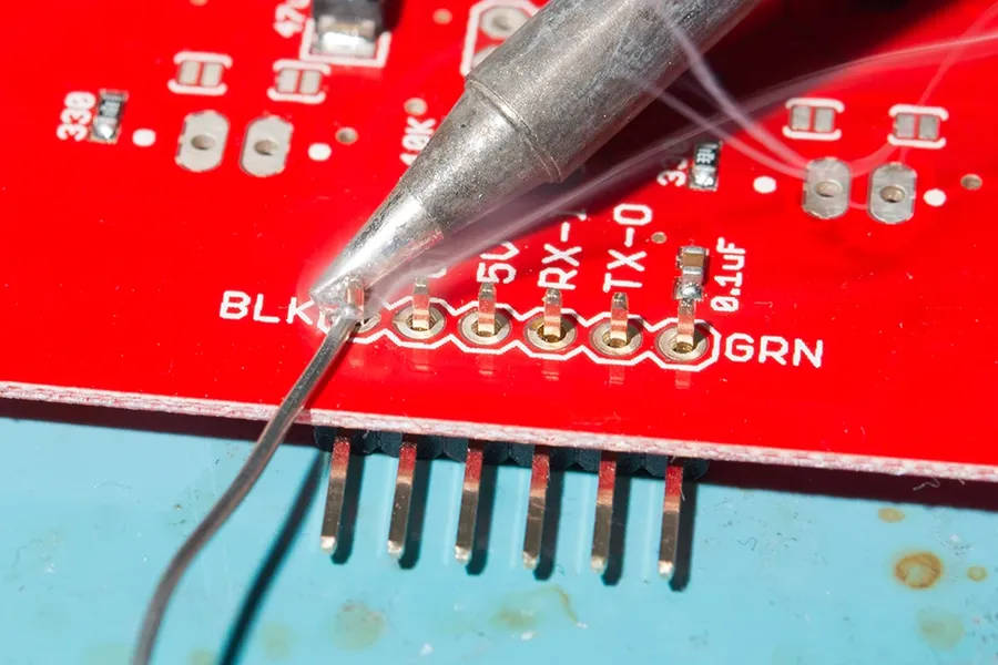 A hand soldering a through-hole component onto a circuit board.